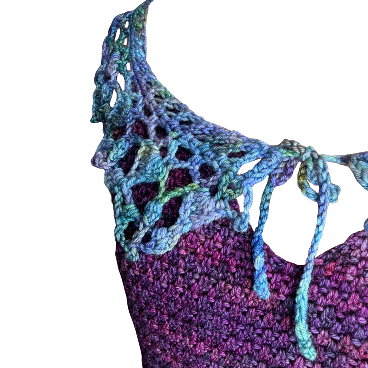 Close-up of a crocheted or knit garment with a lace-up shawl collar in variegated blue, teal, green, and purple yarn, shown against a plain white background.