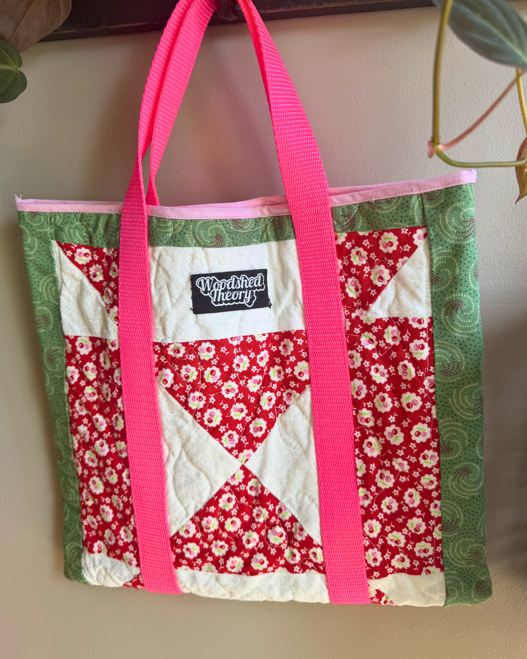 Quilted tote bag with floral pattern and pink handles on a neutral background