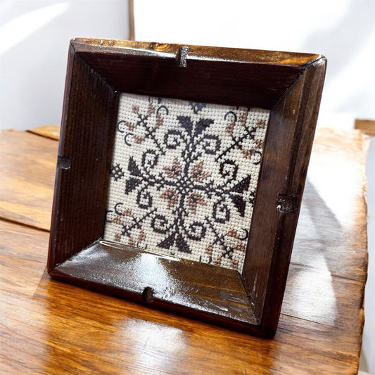 Set of 3 vintage wooden coasters with brown frames, glass covers, and retro cross stitch design in warm tones – perfect for drinks or wall art. display on table