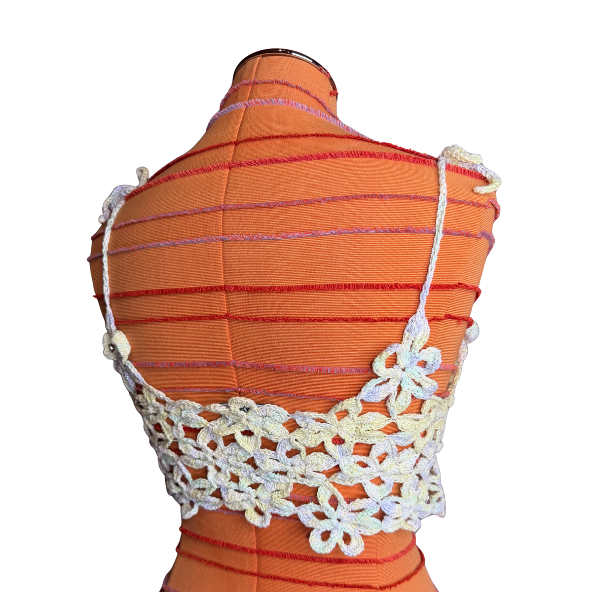 A white crochet floral halter-style top displayed on an orange dress form against a plain white background.