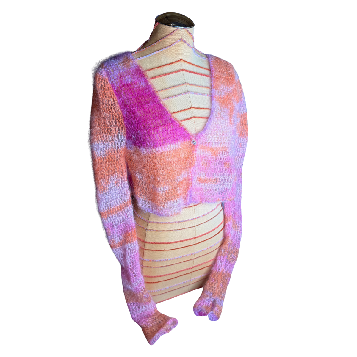 A fuzzy, long-sleeve cropped cardigan sweater with a V-neck, displayed on a beige mannequin torso. The knit pattern features a variegated mix of bright pink, orange, and lavender purple.
