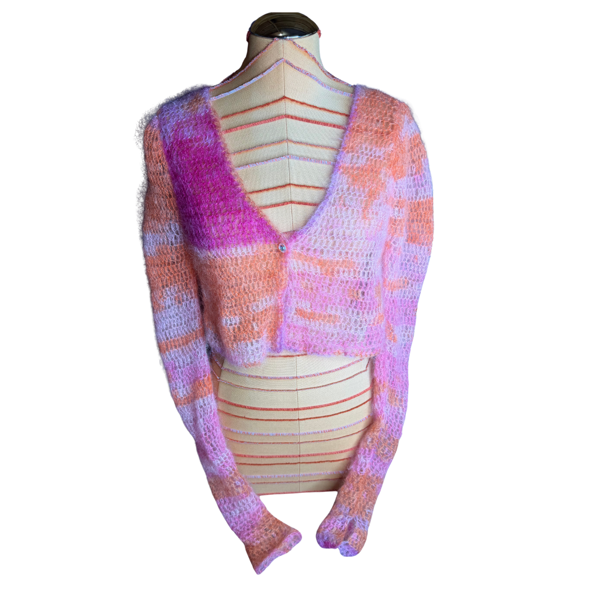 A chunky knit cardigan sweater with a color-shifting yarn pattern in pink, purple, and orange, displayed on a cream-colored dress form mannequin against a white background.