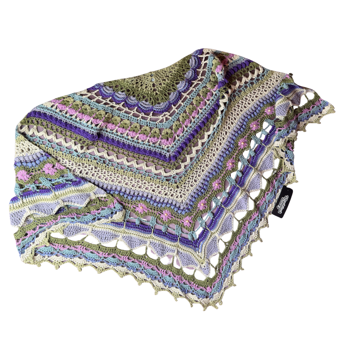 A multicolor crocheted shawl with intricate geometric and floral patterns, featuring stripes of purple, green, pink, and blue on a white background.