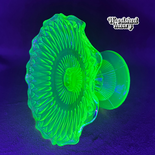 Vintage uranium glass candy or ring dish with ruffled edge and faded gold accents, collectible vaseline glass glowing green under black light. on side glowing