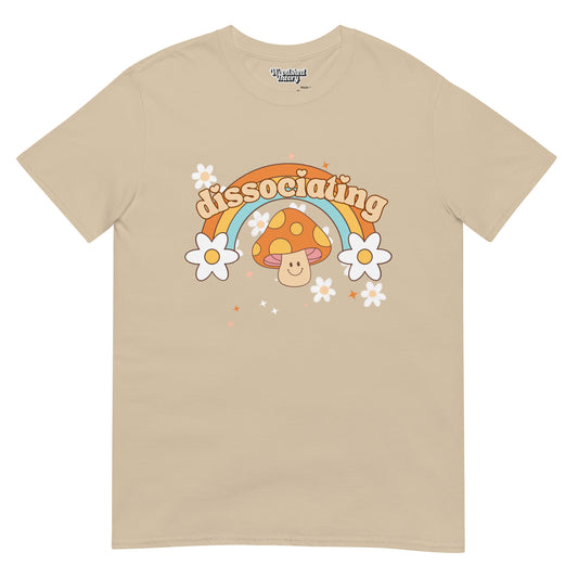 Retro-style t-shirt with rainbow, sparkles, and grinning mushroom with 'Dissociating' text — neurodivergent-friendly graphic tee from Woodshed Theory color sand front flat 